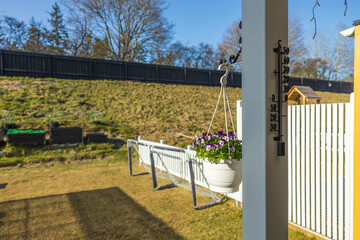 Beautiful view of hanging basket on white pillar with white purple pansies. Sweden.