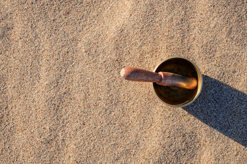 Himalayan tibetian singing bowl on sand, top view. Copy space