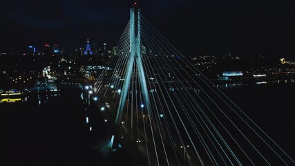 Fototapeta na wymiar Illuminated Holy Cross Bridge (Most Swietokrzyski) at night. Elevated view of cable-stayed bridge over river. Night Warsaw city panorama. 