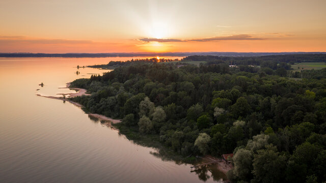Lake Chiemsee in Bavaria with the Alp mountains during sunset from above, coast near village Chieming, during summer.
