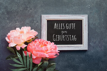Fototapeta na wymiar Alles gute zum Geburtstag means Happy Birthday in German language. Greeting card, peony and paper confetti, circles. Single flower and white frame on black, dark grey distressed textured background.