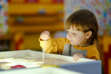 Creative child development. Baby draws sand on glass. Early development of children. Development of...