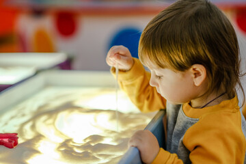 Creative child development. Baby draws sand on glass. Early development of children. Development of...