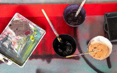 Art palette and vessels with paint and brush close-up on the floor in art studio