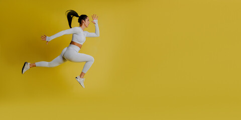 Full length side view of portrait of young fitness sporty woman, wearing white sportswear, posing.