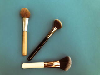 Eye shadow palettes near cracked face powder and cosmetic brushes on pink and crimson