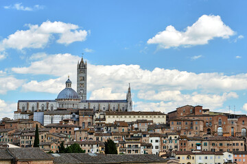 Fototapeta na wymiar Historic houses and bell tower and dome of the medieval cathedral in Siena
