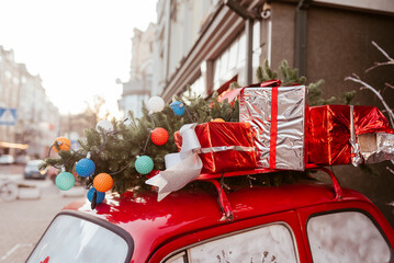 Red retro car with a Christmas tree fir tied to the roof.