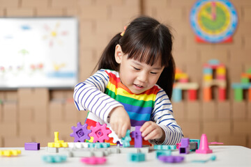 young girl playing gear toy blocks at home