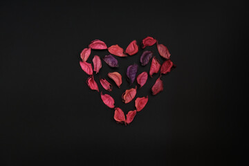 A heart made with pink-purple rose petals black background
