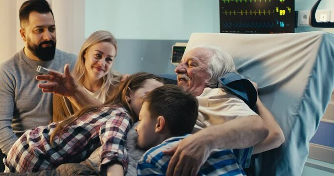 Elderly man hugging grandchildren and talking with parents in clinic