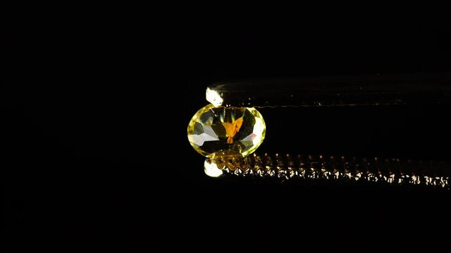 natural heliodor yellow beryl gemstone in the tweezer on the turn table