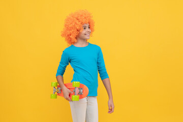 cheerful selfish child girl in curly wig hold penny board, hipster