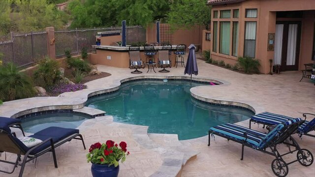 A 4k high definition aerial clip of a desert landscaped travertine tile pool and BBQ. in an Arizona backyard.