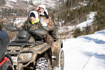 Group of young people riding a quad bike on snow-covered mountains. Carpathians. Ukraine.