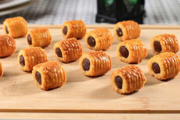 Selected Focus Fresh Baked Pineapple Tart Roll Cookies (Tart Nanas or Kuih Nenas) on Wooden Background. Before Sale at Eid Mubarak