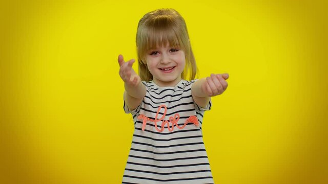 Come to me, I want to embrace you. Funny playful blonde child girl 5-6 years old spread hands and give hug to you. Pleasant expression love feelings on yellow studio wall background. Teen kid children