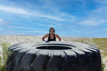 beautiful fitness woman doing exercise pushing big tire on hill, workout