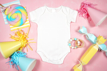 Baby wear romper bodysuit, Birthday and parties theme SVG craft product flat lay mock up. Styled with pink, blue and yellow party hats and bon bons on a textured pink background.