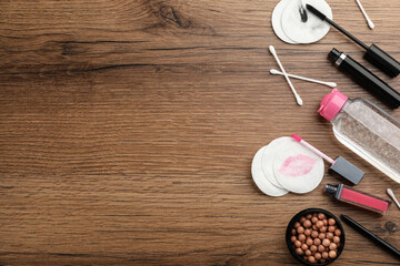 Dirty cotton pads, swabs, cosmetic products and micellar cleansing water on wooden background, flat lay. Space for text