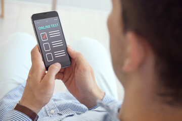 Man using smartphone for online test indoors, closeup