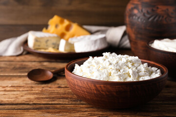 Clay bowl with cottage cheese on wooden table, space for text