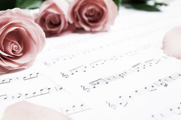 Beautiful roses, focus on sheet with music notes. Space for text