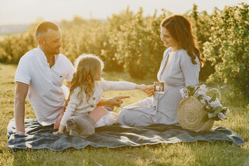 Family with little daughter spending time together in sunny field