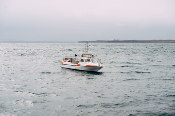 White fishing motor boat sails across the Atlantic Ocean in Iceland. Side view