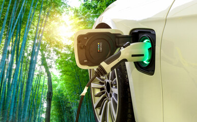 EV Car or Electric car at charging station with the power cable supply plugged in on blurred nature with soft light background. Eco-friendly alternative energy concept	