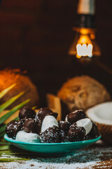 Concept of coconut candy with a ripe half cut coconut with green leaves on a brick wall background