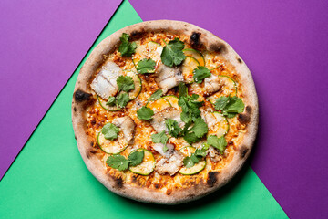 White fish fillet pizza, top view on green and purple background