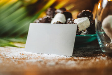 Concept of coconut candy with a ripe half cut coconut with green leaves on a brick wall background