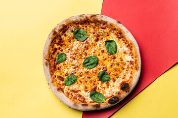 Cheese pizza on red and yellow background, directly above view