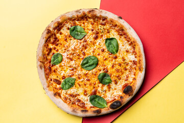 Cheese pizza on red and yellow background, directly above view