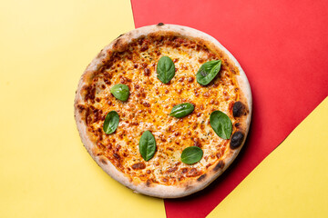 Cheese pizza on red and yellow background, directly above view