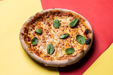 Cheese pizza on red and yellow background, directly above view
