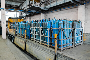 Fototapeta na wymiar A bundle of oxygen cylinders with compressed gas secured on yellow skids in platform. Blue Oxygen tanks for industry. Liquefied oxygen production. Factory.