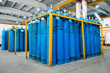A bundle of oxygen cylinders with compressed gas secured on yellow skids in platform. Blue Oxygen...