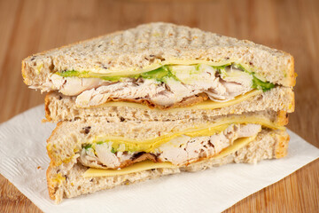 Detailed closeup of shredded roast chicken, sliced cheese and avocado on multigrain bread.