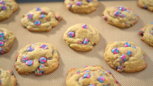 Freshly baked unicorn chocolate chip cookies on a baking sheet lined with a silicone mat.