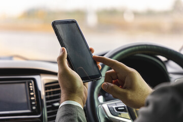 Young man using smartphone while driving car. Using a smartphone while driving is at risk of being involved in accidents and dangerous.