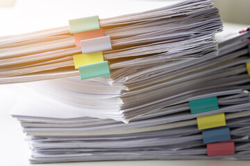 Piles of white papers work large piles of papers stacked together. On the desk in the office with colorful clip. Documents that are not finished in the office. Business concept.