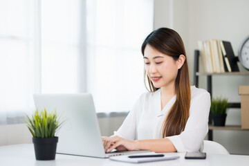 Young asian beautiful business woman working with laptop sitting at home. Smiling charming happy young female doing homework meeting conference with team at home.
