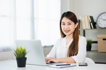 Young asian beautiful business woman working with laptop sitting at home. Smiling charming happy young female doing homework meeting conference with team at home.