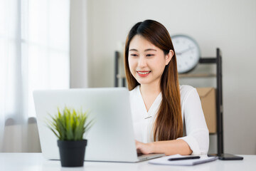 Young asian beautiful business woman working with laptop sitting at home. Smiling charming happy young female doing homework meeting conference with team at home.