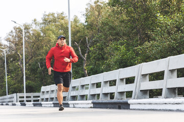 Young asian man wearing sportswear running outdoor. Portraits of Indian man jogging on the road. Training athlete outdoor concept.