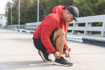 Runners tie their shoelaces prepared to run outdoors. Young asian man wearing sportswear running outdoor.Training athlete work out at outdoor concept.