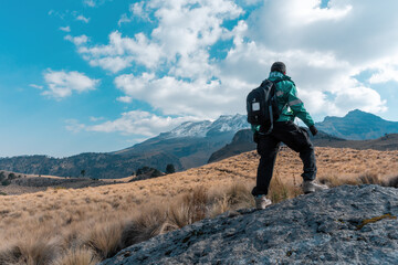 A back view of a tourist with a backpack and the Iztaccihuatl volcanic mountain in the background