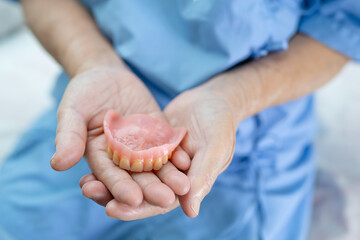 Asian senior or elderly old woman patient holding to use denture in nursing hospital ward, healthy strong medical concept